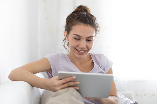 Young woman reads from digital tablet at home