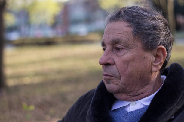 istock Senior man sitting on bench in the park 1195465135