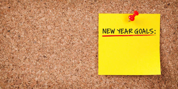 istock Yellow Sticky Note With New Year Goals And Red Push Pin On Cork Board 1195466473
