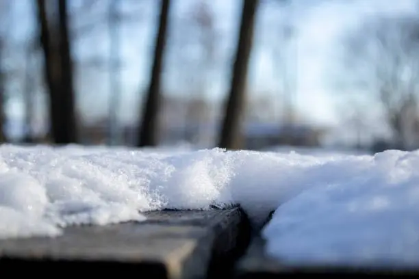 Close up shot of snow resting on a park picnic table