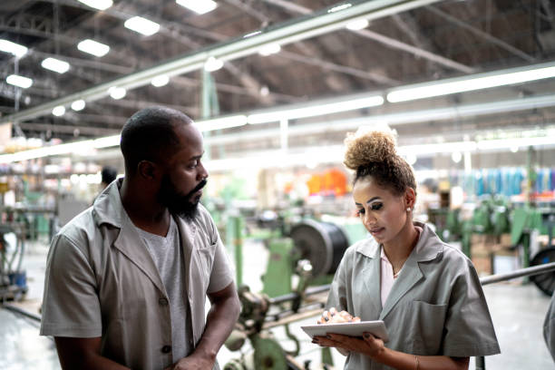 istock Coworkers using digital tablet and working together in a factory 1195471257