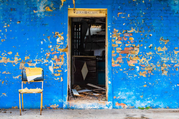 Open doorway abandoned vintage brick wall Police Canteen building with stripping blue surface paint Open doorway abandoned vintage brick wall Police Canteen building with stripping blue surface paint on facade, no door and rubble/ junk inside. Forgotten old property with walls cracked falling apart. falmouth harbor stock pictures, royalty-free photos & images