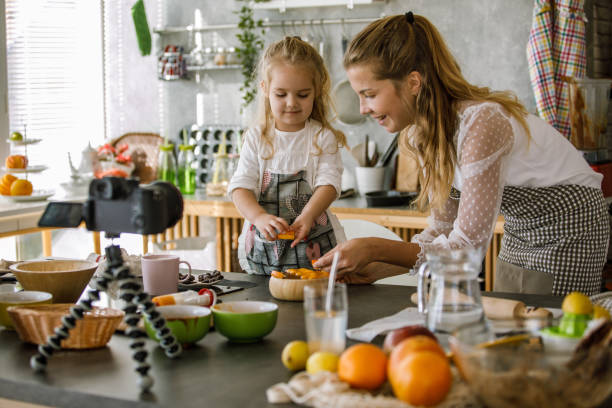 istock Toddler assisting her mother while decorating a dessert and filming a video 1195481617