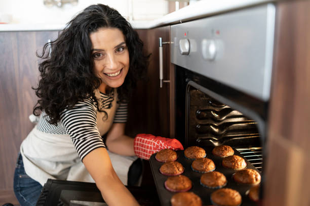 istock Woman putting tray in oven 1195482785
