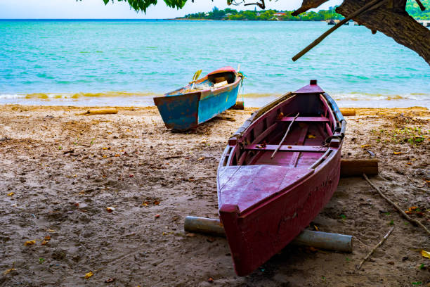 Old wooden fishing boats docked on sea shore/ seashore on white sand beach coast landscape with empty fish nets and paddles mounted/ rolled on logs. Old wooden fishing boats docked on sea shore/ seashore on white sand beach coast landscape with empty fish nets and paddles mounted/ rolled on logs. Sunny summer day on tropical Caribbean island. falmouth harbor stock pictures, royalty-free photos & images