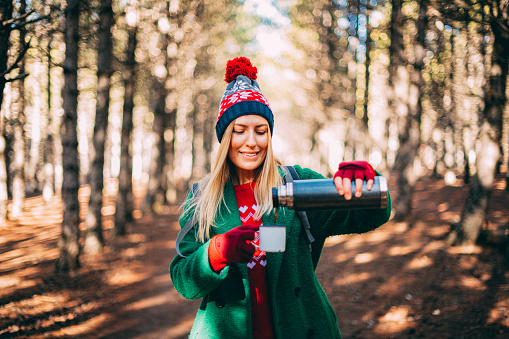 Woman Filling Coffee From Thermos in Forest
