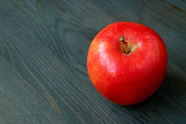 istock Red apple isolated on dark colored wooden table with copy space 1195486620