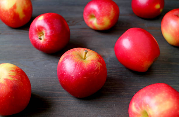 istock Fresh red apples scattered on dark colored wooden table 1195486625