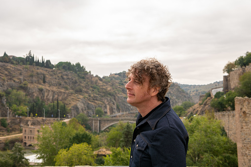 A man overlooks the scenery of the beautiful,historic city of Toledo, Spain. Profile view.