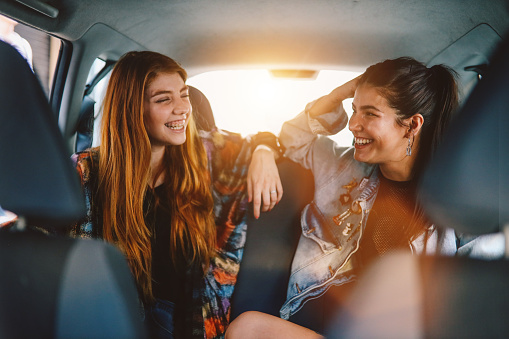 Two young beautiful women laughing and sitting in the backseat of a car in Buenos Aires, Argentina.