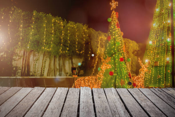 istock Rustic wood table in front of christmas light night,abstract circular bokeh background. Christmas table background. Beautiful xmas gift boxes on floor near fir tree in front lawn. 1195498054