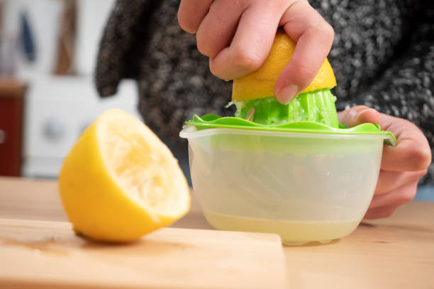 istock Close up of a woman's hand squeezing lemon on wooden table 1195498133