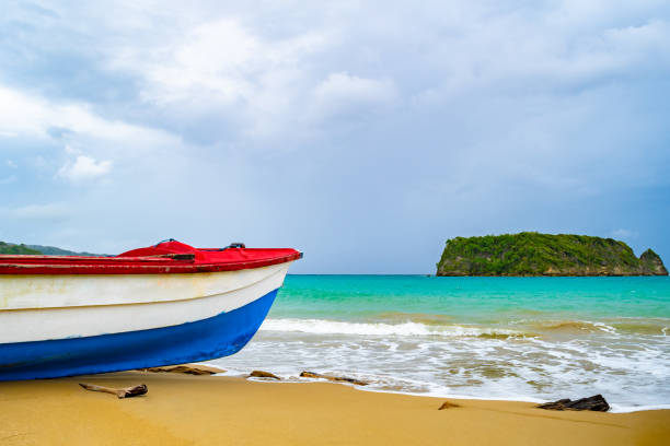 colorful old wooden fishing boat docked by water on a beautiful beach coast. white sand sea shore landscape on tropical caribbean island - cabarita beach imagens e fotografias de stock