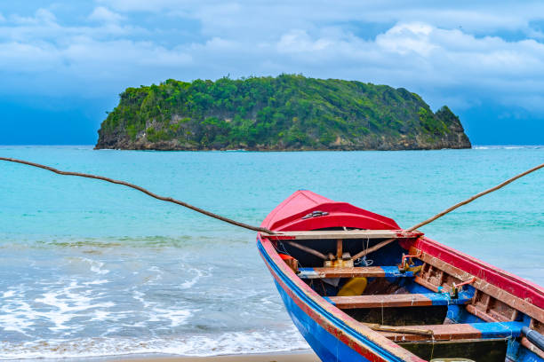 colorful old wooden fishing boat docked by water on a beautiful beach coast. white sand sea shore landscape on tropical caribbean island - cabarita beach imagens e fotografias de stock