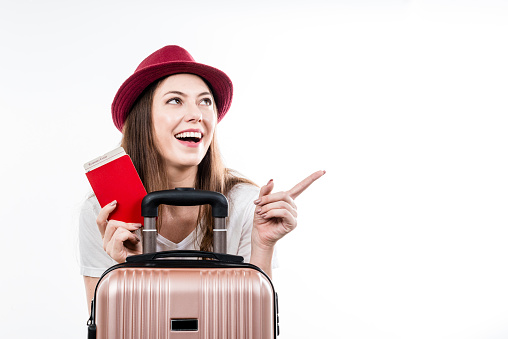 Beautiful happy woman sitting holding her luggage, passport, map and ticket for boarding. Air flight journey concept.