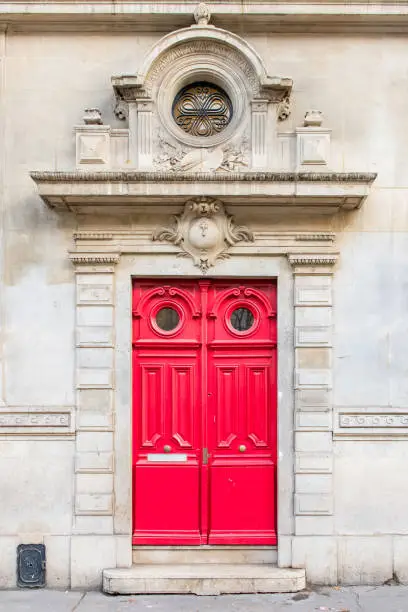 Paris, beautiful red wooden door, typical building in the Marais, with carved lintel