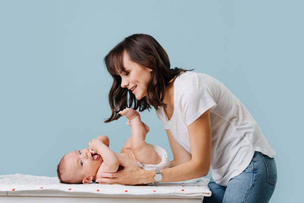 mother bent over her infant talking, caring and playing with him stock photo