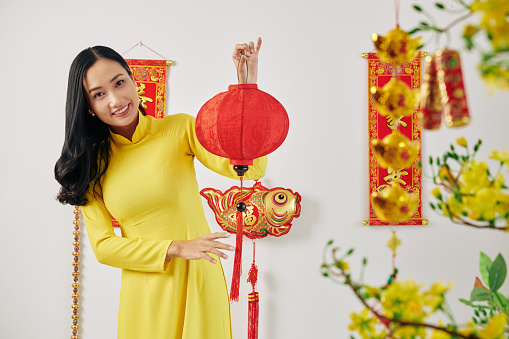 Beautiful young Asian woman showing red and gold decorations for Chinese New Year