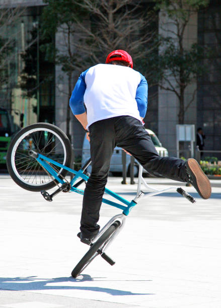 A young male BMX rider executes a mid-air trick at an outdoor skate park on a sunny day.