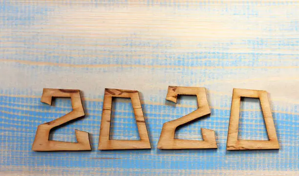 the cut numbers form the number 2020 on a partially painted wooden surface