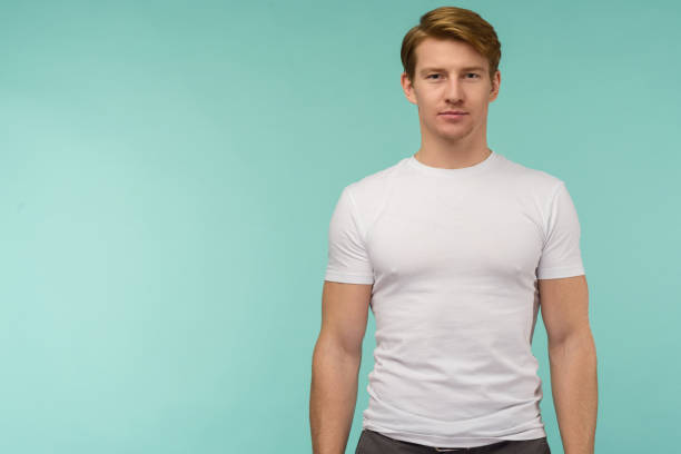 istock Athletic young man standing in white thirt on blue background 1195537046