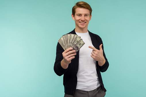 Handsome sporty red-haired guy pointing finger money on a blue background. - image