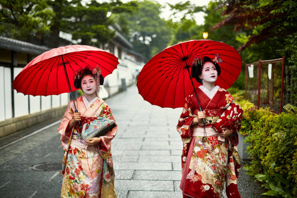 istock Two Young Japanese Maiko Walking with Umbrellas in Rain 1195538589