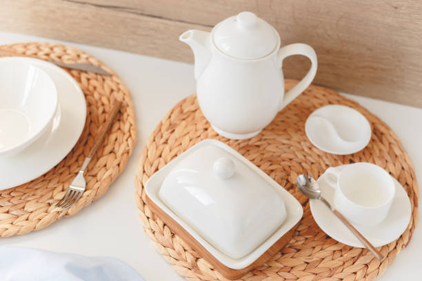 istock White ceramic tableware, fibre braided round placemat and cutlery set on white background. Scandinavian style. 1195542518