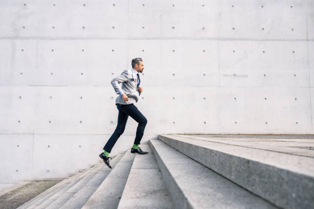 businessman running up stairs outdoors elegant bearded businessman running up stairs  of concrete building staircase stock pictures, royalty-free photos & images