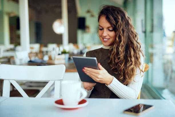 istock Attractive young curly brunette looking at her tablet and smiling 1195546599
