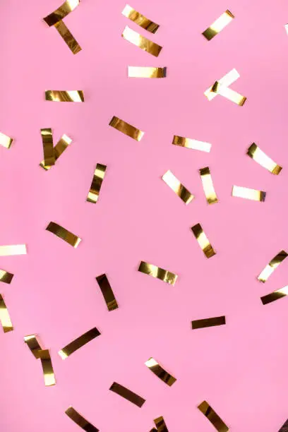 Gold confetti on pink background. Flat lay, top view.