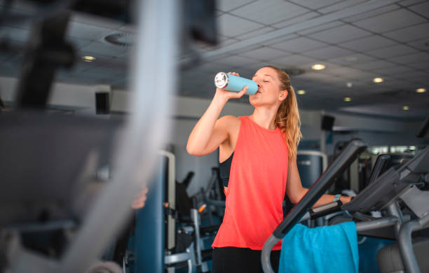 istock Woman Drinking Water While Working Out on Cross Trainer 1195550030