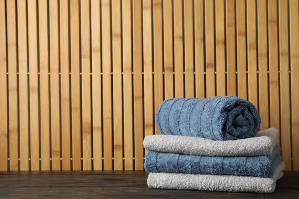 istock Folded towels on wooden table against bamboo background, space for text 1195550880