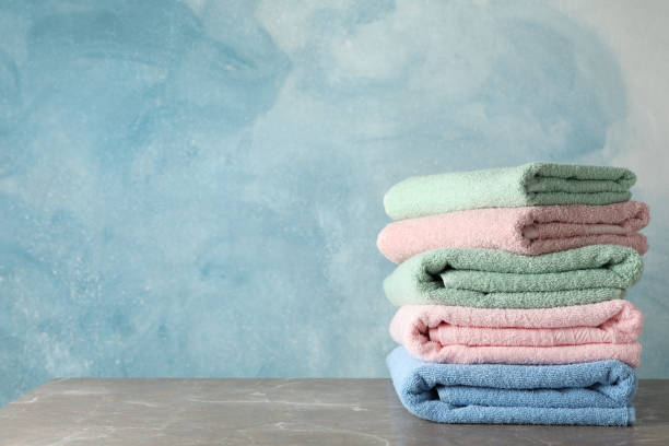 istock Stack of color towels on grey table against blue background, space for text 1195550950