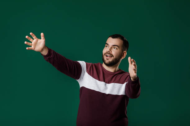 bearded young man standing with raised arms bearded young man standing with raised arms. man wants to hug a friend. greeting gesture male is standing and shows outstretched hand with open palm stock pictures, royalty-free photos & images