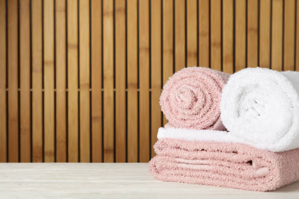 istock Folded towels on wooden table against bamboo background, space for text 1195552349