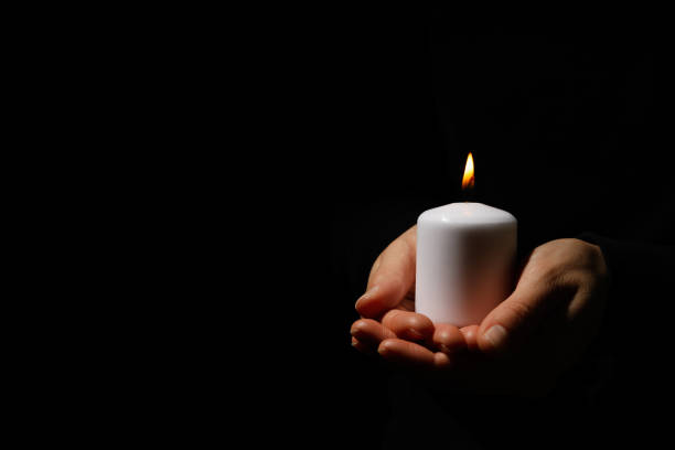 Woman holds candle on black background, space for text