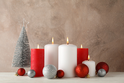 Burning candles, christmas tree and balls against brown background, space for text