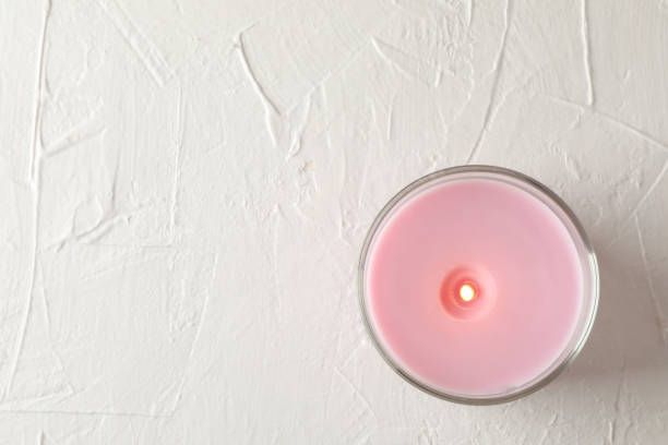 Pink candle in glass jar on white background, top view