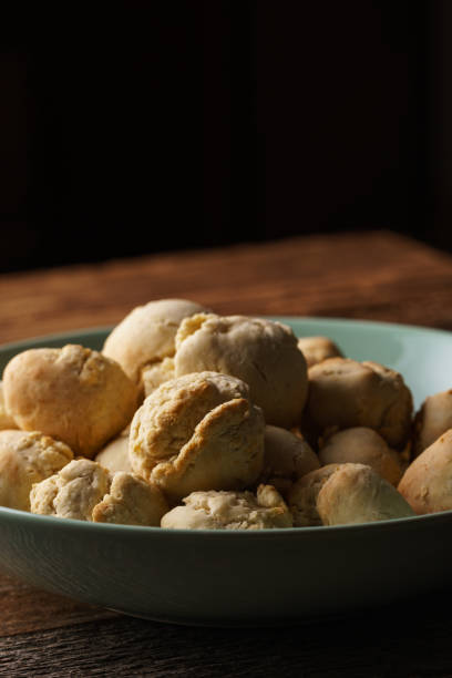 Homemade vegan garlic bread buns made of pizza dough balls filled with herb butter, as side dish, mint green bowl on wooden table, dark background - close-up, angled view, vertical format, copy space mini bollos de pizza veganos caseros hechos de bolas de masa de pizza llenas de mantequilla de ajo, como guarnición, cuenco verde menta sobre la mesa de madera, fondo oscuro - vista de cerca, vista en ángulo, formato vertical, espacio de copia