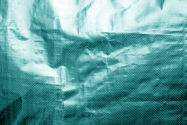 istock Metalized plastic wrap texture with crumples in cyan tone. 1195555722