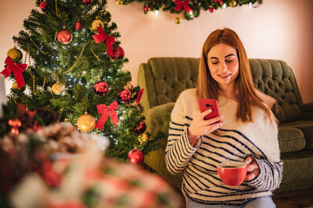 istock Woman using phone and drinking coffee for Christmas 1195555818