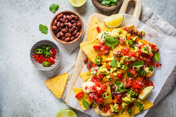 Nachos chips with cheese sauce, guacamole, salsa and vegetables on the board, top view. Party food concept. Nachos chips with cheese sauce, guacamole, salsa and vegetables on the board. Party food concept. Mexican food concept. nacho chip stock pictures, royalty-free photos & images