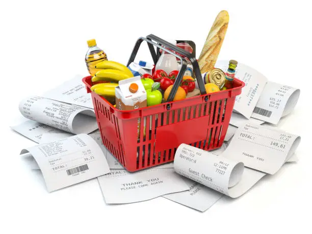 Photo of Grocery expenses budget  and consumerism. Shopping basket with foods on the pile of receipt isolated on white.