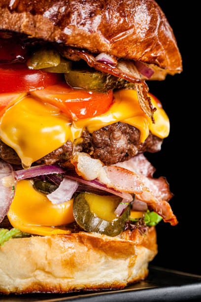 アメリカ料理。二重肉カツ、ベーコン、トマト、キュウリ、チーズ、頭蓋骨、赤玉ねぎ、ソースの大きなロイヤルバーガー。コピースペース、背景画像 - symmetry burger hamburger cheese ストックフォトと画像