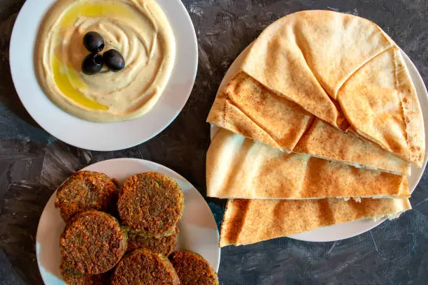 Photo of Tahini sauce, pita bread and falafel on gray background.