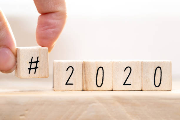 istock Hashtag 2020 concept, hand change wooden cubes close-up with white background 1195562646