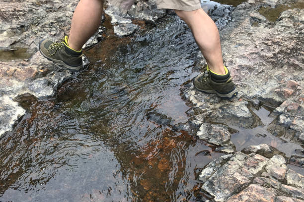 istock A man wearing hiking boot and crossing the river 1195564816