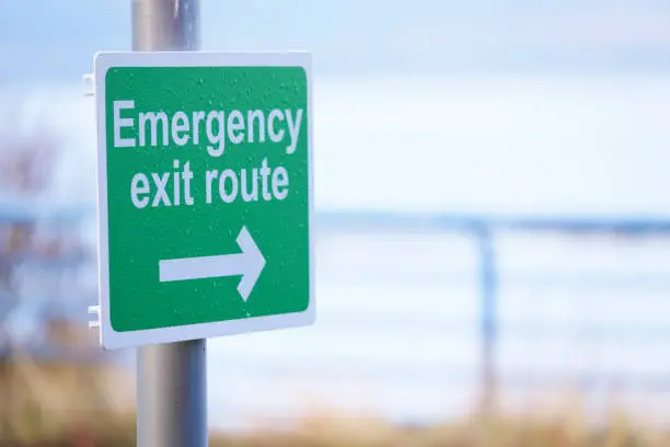 Emergency escape route green sign with direction arrow uk