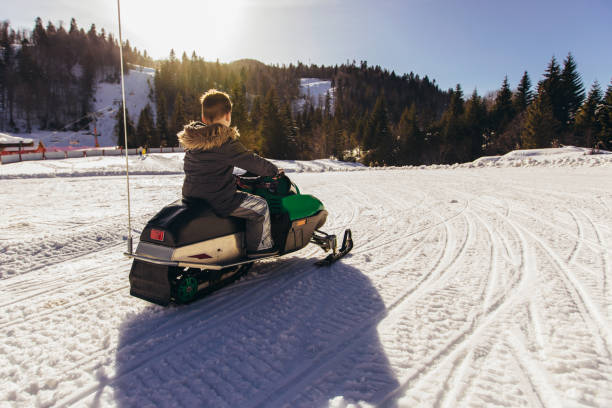 istock Boy driving snowmobile in a winter landscape 1195572612